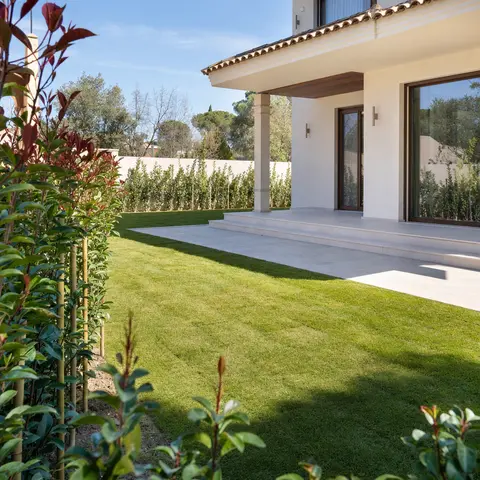Jardín de obra nueva con tepe recién extendido y seto joven entutorado